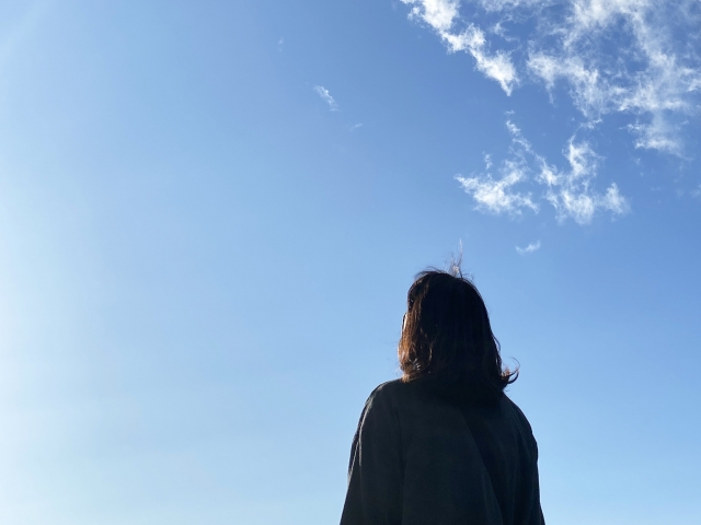 空を眺めて１人立つ女性