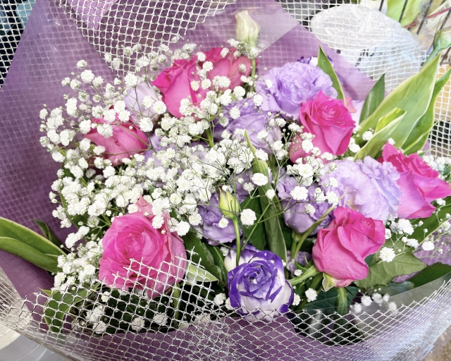 ピンクと紫のバラとその周りにちりばめられたカスミソウの花束